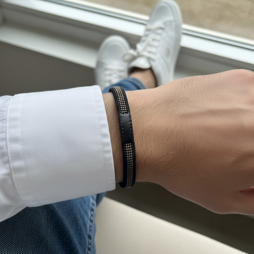 Læderarmbånd på håndled med sort vævet perlesnor og spændedetaljer