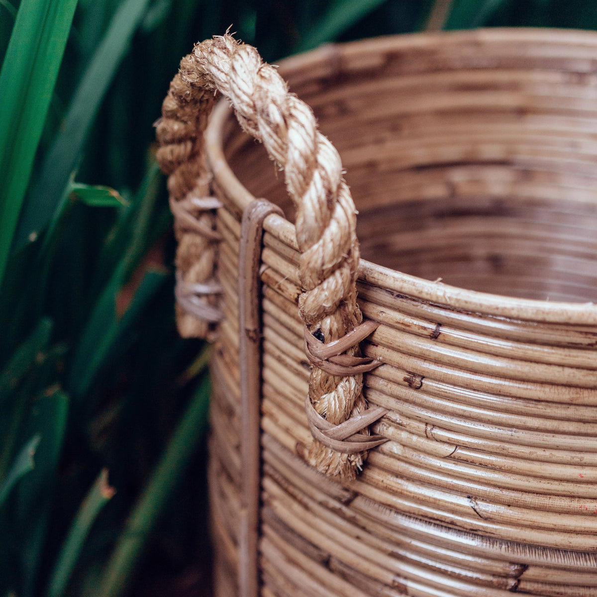 Detalje af rattan-kurv med flettede håndtag og tæt kantomfletning.